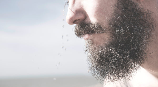 man with curly beard about to use beard oil