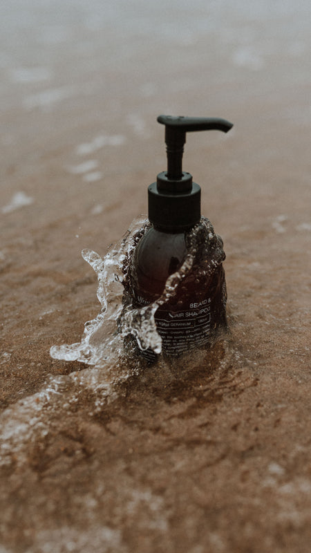amber beard shampoo bottle on sandy shore